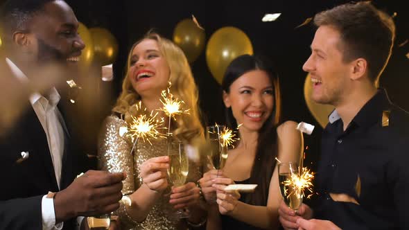 Smiling Multiracial Couples With Champagne Glasses and Bengal Lights, Party