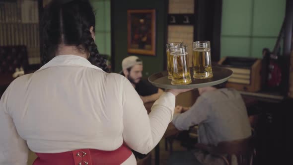 Cute Fat Girl with Three Glasses of Beer on a Tray in a Beer Restaurant