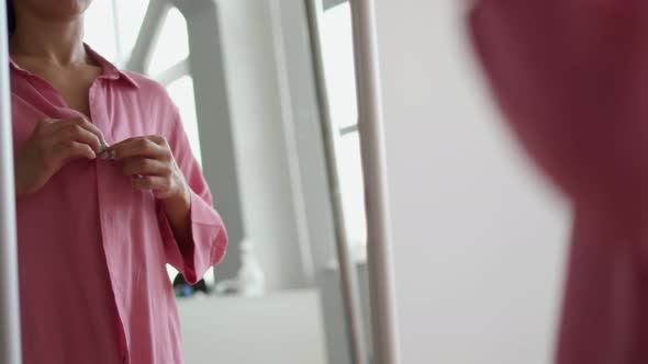 From the Back Woman Puts on Pink Shirt and Preens in Front of Mirror at Home