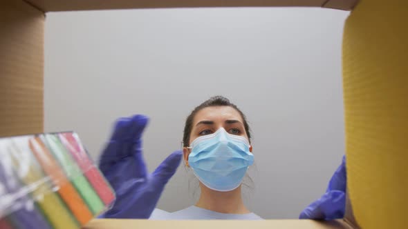 Woman in Mask Taking Cleaning Supplies From Box