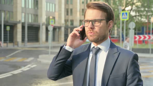 Businessman Talking on Phone while Walking in Street