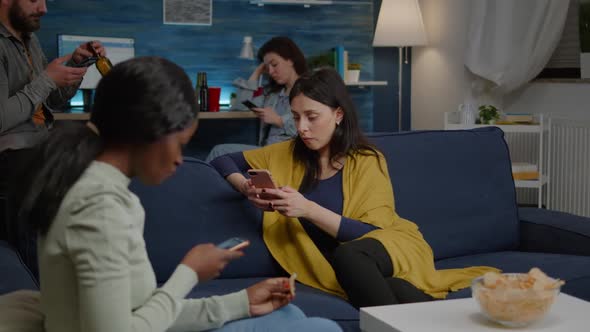 Multiracial Friends Relaxing on Couch While Surfing News on Internet Using Mobile