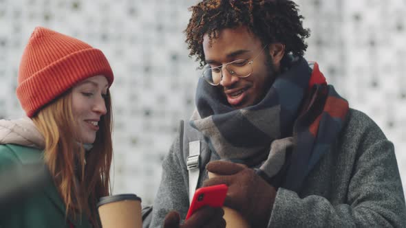 Multiethnic Man and Woman Using Smartphone and Speaking Outdoors