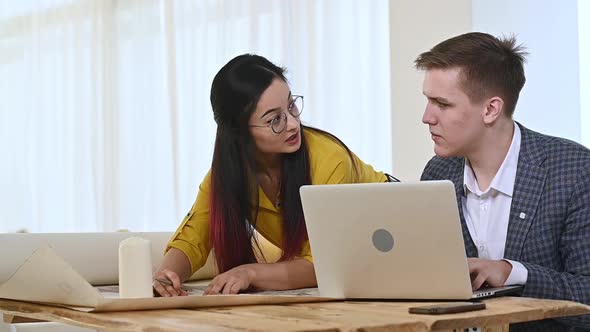Asian woman and a European man work in a design office and discussing