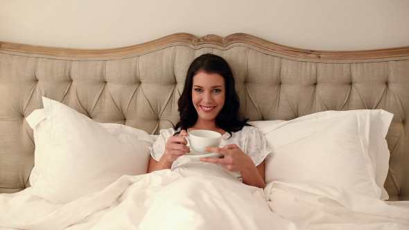 Beautiful Brunette Lying In Bed Drinking Coffee