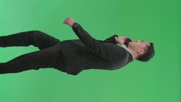Side View Of Asian Business Man Talking On Mobile Phone While Walking On Green Screen Chroma Key