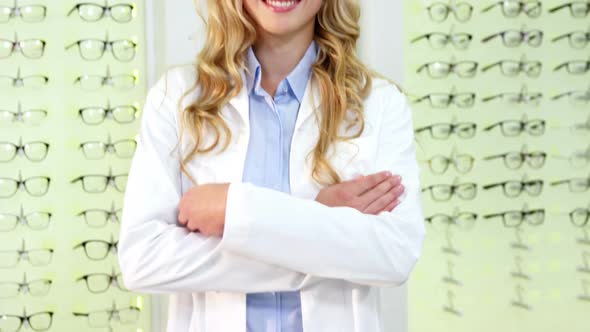 Beautiful optometrist standing with arms crossed at ophthalmology clinic