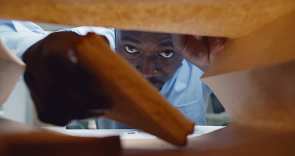 View From Inside Paper Bag of African Businessman Take Sandwich and Bite Smiling at Camera