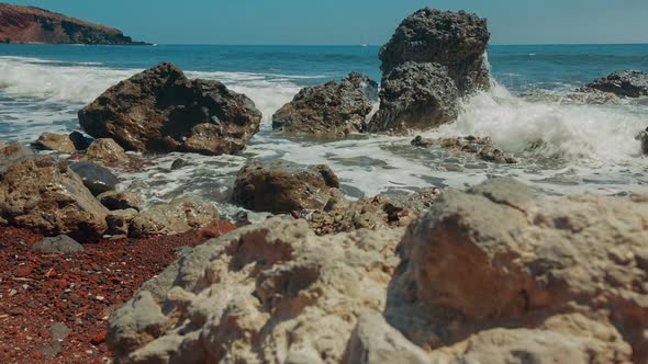 Slider Shot of Mediterranean Volcanic Beach with Red Sand and Surf Hitting the Rocks