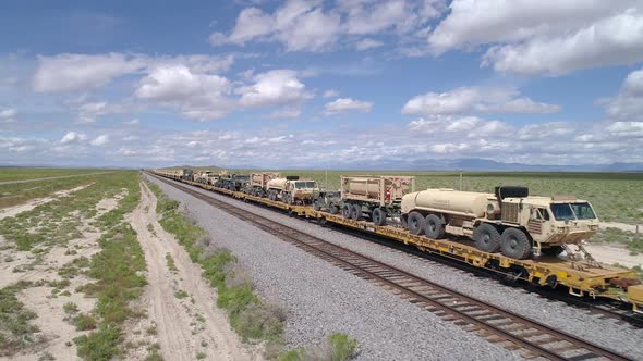 Train transporting load of military vehicles through the desert