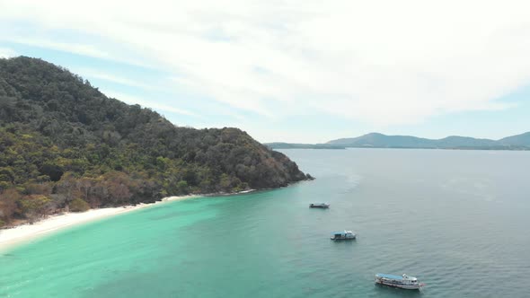 Moored tourist tour boats in line off the coast of Coral Island over Emerald sea of South Thailand