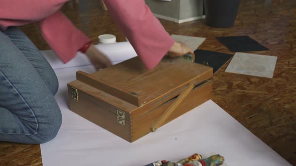 Girl Artist Disassembles an Easel for Drawing Pictures in a Design Studio