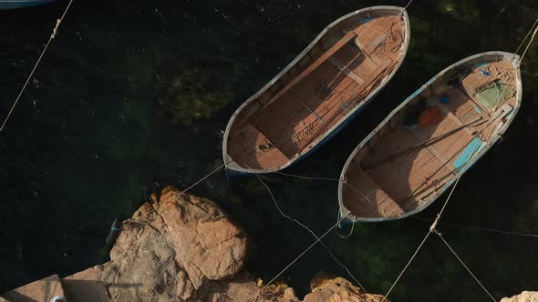 Old Empty Boats Being Moored in Clear Shallow Water By the Rocks