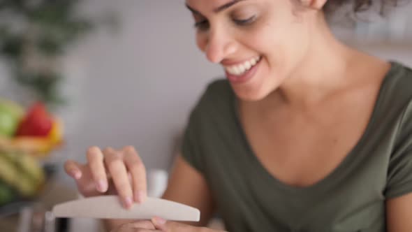 Tilt up video of happy woman doing manicure at home. Shot with RED helium camera in 8K.