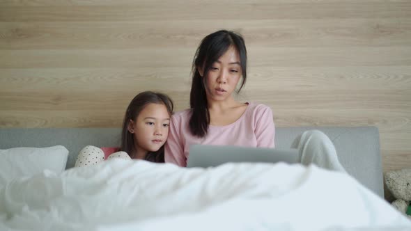 Serious Asian mom and daughter looking at laptop