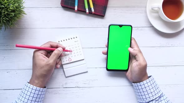 Deadline Concept with Hand Marking Date on Calendar and Using Smart Phone