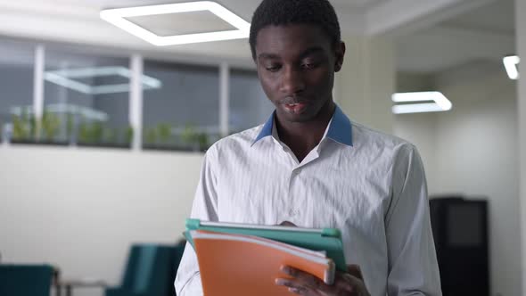 Focused Young African American Male Manager Messaging Online on Tablet Looking Aside Smiling