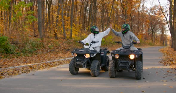 A Young Couple Rides an ATV Offroad in the Autumn Forest