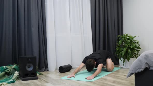 Young athlete stretches hamstring and hip muscles on yoga mat. Stretching and yoga concept