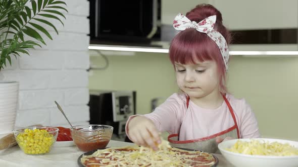 Cooking Pizza. Little Child in Apron Adding Grated Cheese To Dough in Kitchen