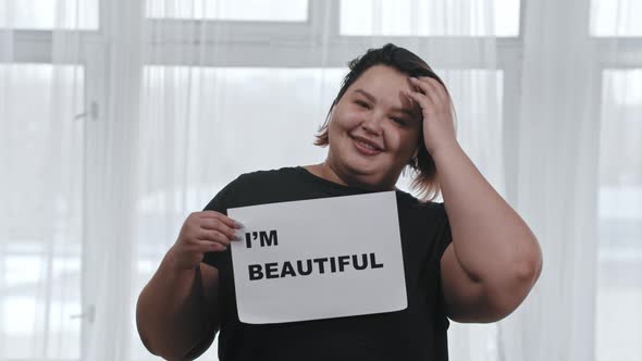 Concept Body Positivity Fat Woman Holds a Sign with the Inscription I'M BEAUTIFUL Looking in the