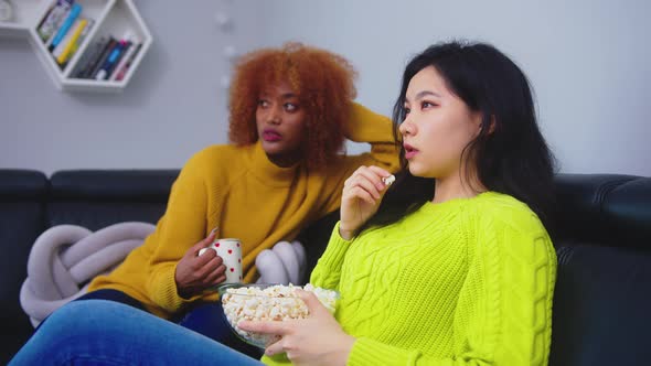 Multiracial Friendship. Afican American Black and Asian Woman Eating Popcorns Gossiping and Watching