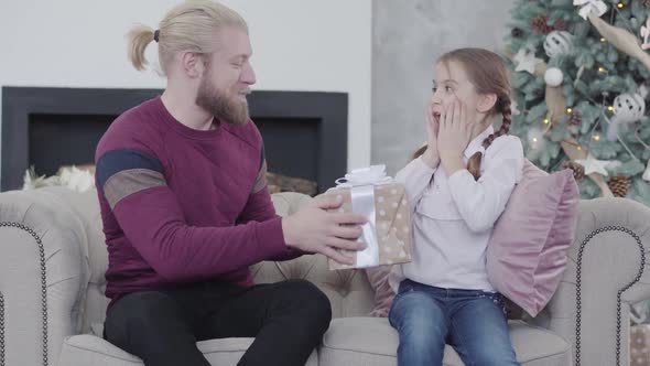 Happy Caucasian Man Giving Christmas Gift To His Lovely Daughter, Excited Teenage Girl Taking