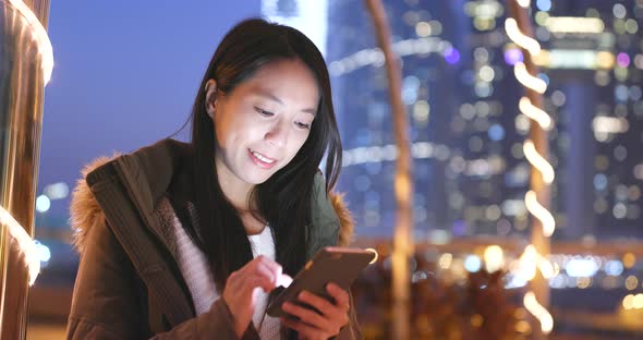 Woman Use of Smart Phone in The City at Night, Urban Cityscape Background of Hong Kong