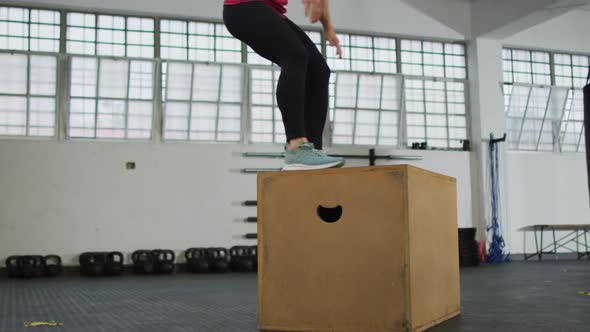 Fit caucasian woman jumping on pylo box at the gym