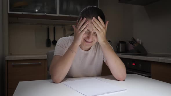Upset Stressed Woman Crying on Kitchen at Night After Getting Bad News and Reading Documents