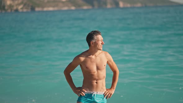 Relaxed Muscular Athletic Man on Beach Against Turquoise Water of Mediterranean Sea in Oludeniz