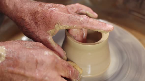 Potter's Hands Hold Clay Jug on Potter's Wheel and Give It Smooth Shape with Wet Sponge