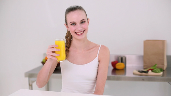 Smiling Model Drinking Glass Of Orange Juice