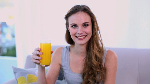 Happy Model Drinking Orange Juice On The Couch