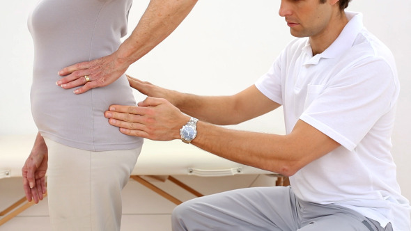 Physiotherapist Touching Senior Patients Hips