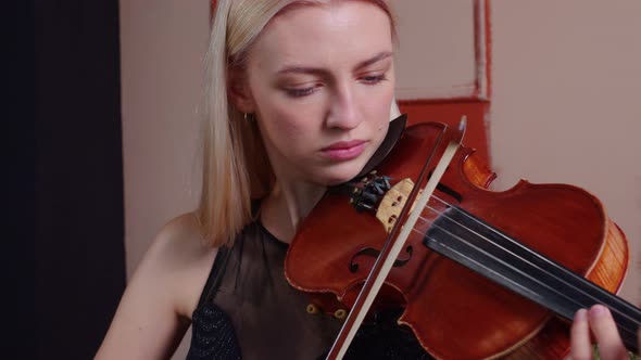 Young Woman Passing Bow Over Strings of Fiddle