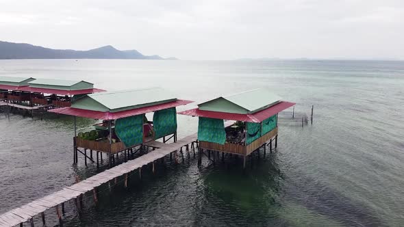 Drone Fly Over a Pier in Asia with Local Restaurant and a Boat Moving in the Sea