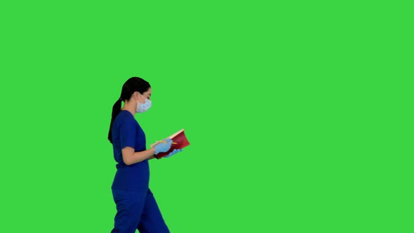 Young Indian Female Doctor Walks with Notebook on a Green Screen Chroma Key