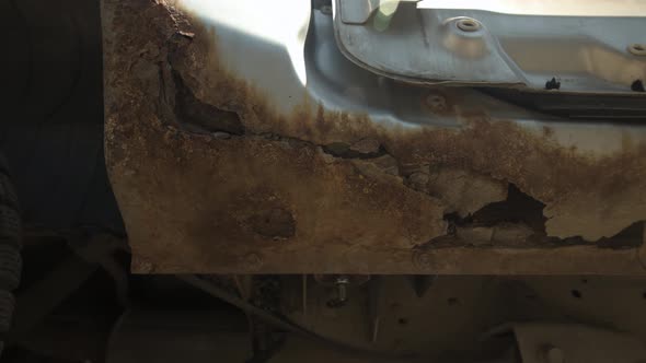 Closeup of Destructive Punchthrough Corrosion on a Silver Car