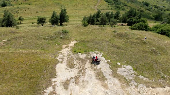 Man in a Black Cap and Red T-shirt on a Colored ATV Rides