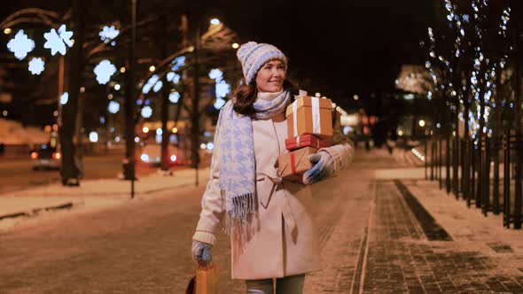 Happy Woman with Christmas Gifts Walking in Winter