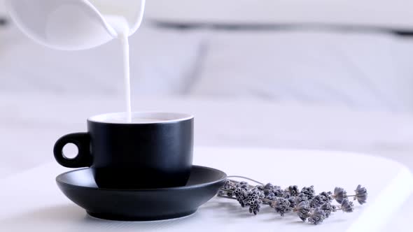 Pouring milk in hot coffee. Morning breakfast concept. Breakfast in bed