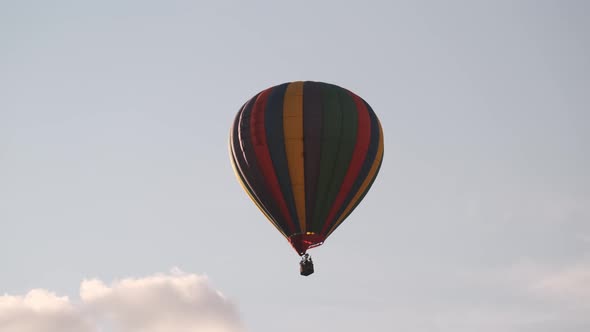 Slomo tracking shot of colorful hot air balloon floating away in blue sky