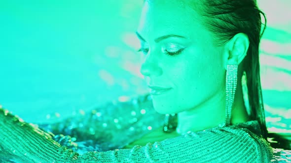 Beautiful Woman Posing in Pool Water Under Neon Color Light