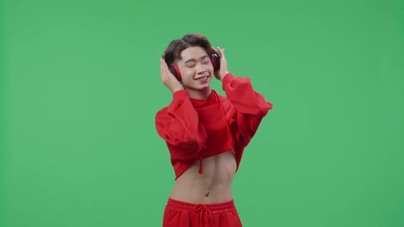 Asian Transgender Male Listening To Music With Headphones And Dancing In The Green Screen Studio