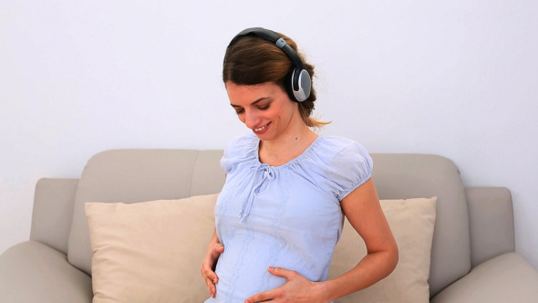 Pregnant Woman Listening To Music On The Couch