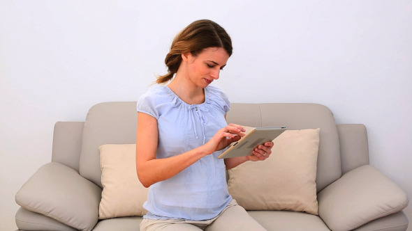 Pregnant Woman Using Her Tablet Pc On The Couch