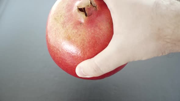 Male Hand Puts the Ripe Pomegranate on the Table, Closeup