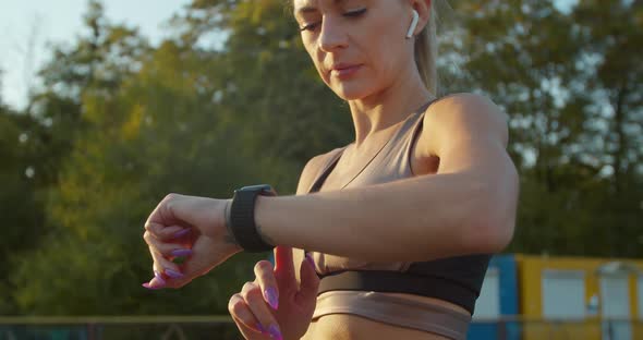 Sportswoman Using Smart Watch and Listening To Music During Morning Training