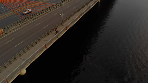 Woman in Bright Clothes Riding Bicycle on Bridge